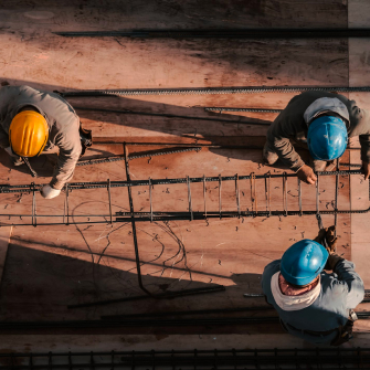 Three construction workers tie off rebar into a cage